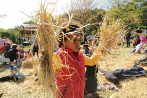 Child holding straw to fill up scarecrow