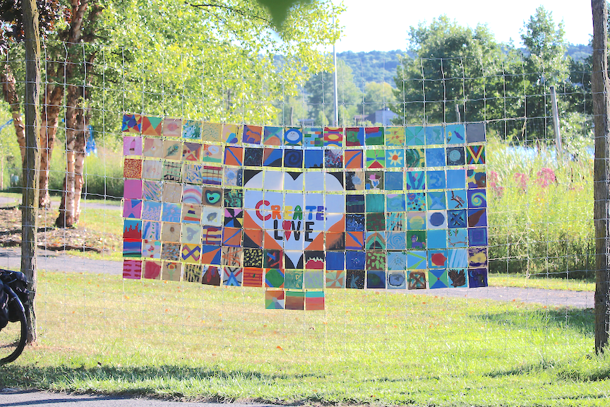 Colored tile mosaic, in the center, surrounded by a white heart as the words "Create Love". Installation at Ithaca Children's Garden in Ithaca, New York.