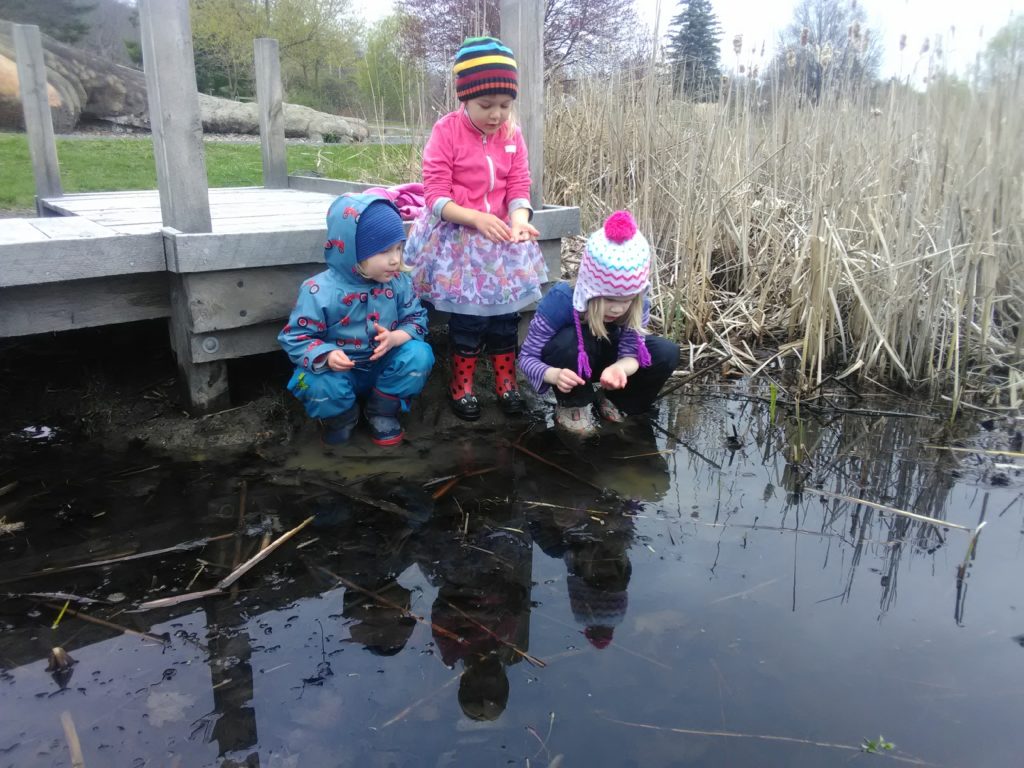 Three small children stand in the bioswale