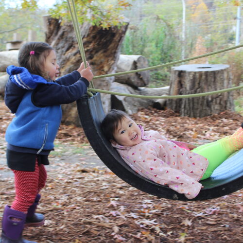 Two children play on a plastic swing