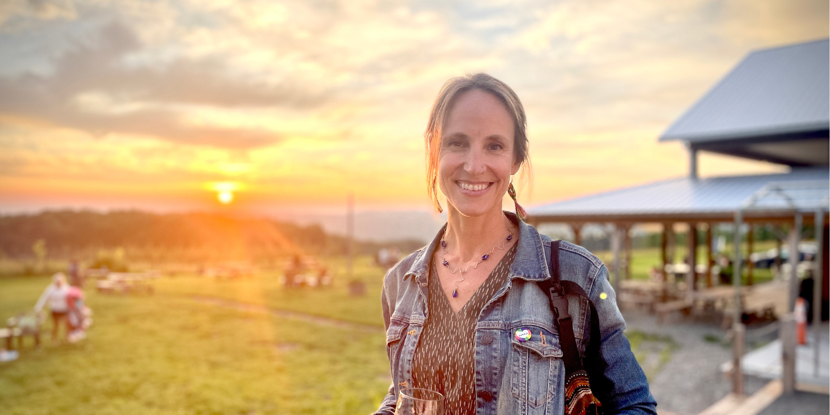 Erin Marteal, ICG's new Development Director, stands in front of a sunset. She's smiling at the camera.