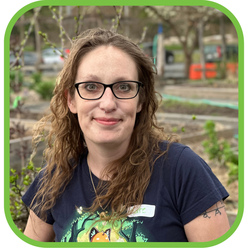 A person wearing glasses standing in front of a vegetable garden.