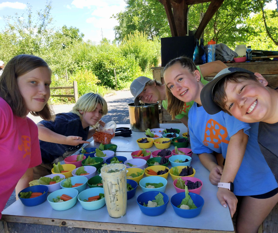 Five counselors in training show off the bowls of snacks they made