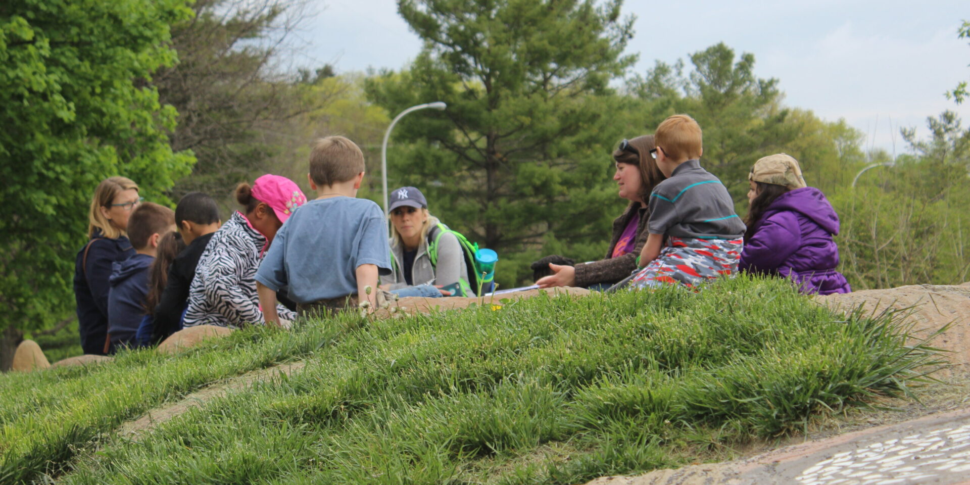 A group of adults and kids sits on Gaia, the turtle sculpture's back.