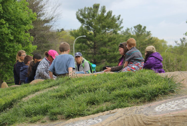 A group of adults and kids sits on Gaia, the turtle sculpture's back.