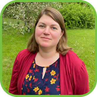 A woman stands in a garden setting.